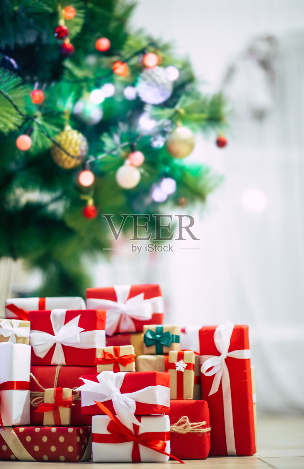 用彩灯装饰的圣诞树和许多彩色的礼盒在家庭的房间里照片摄影图片