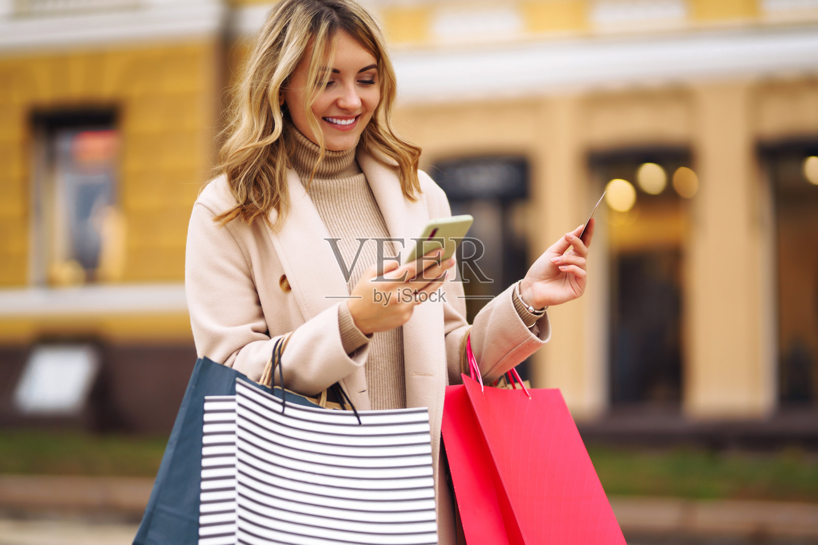 一个年轻女人带着电话和信用卡在城市的街道上。照片摄影图片