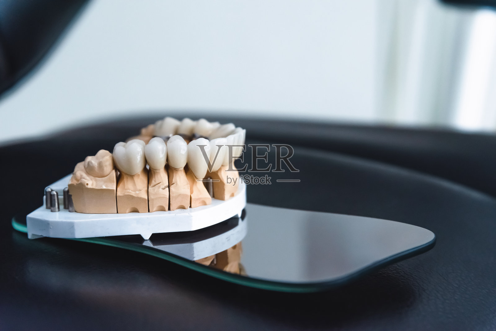 在牙科诊所的手术镜上，镶有锆冠的人造颌。牙科和治疗概念照片摄影图片