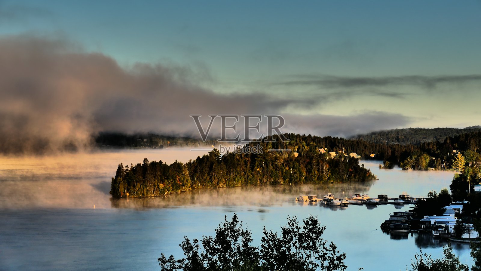 日出时，森林环绕的水面上有雾，还有一个岛屿照片摄影图片