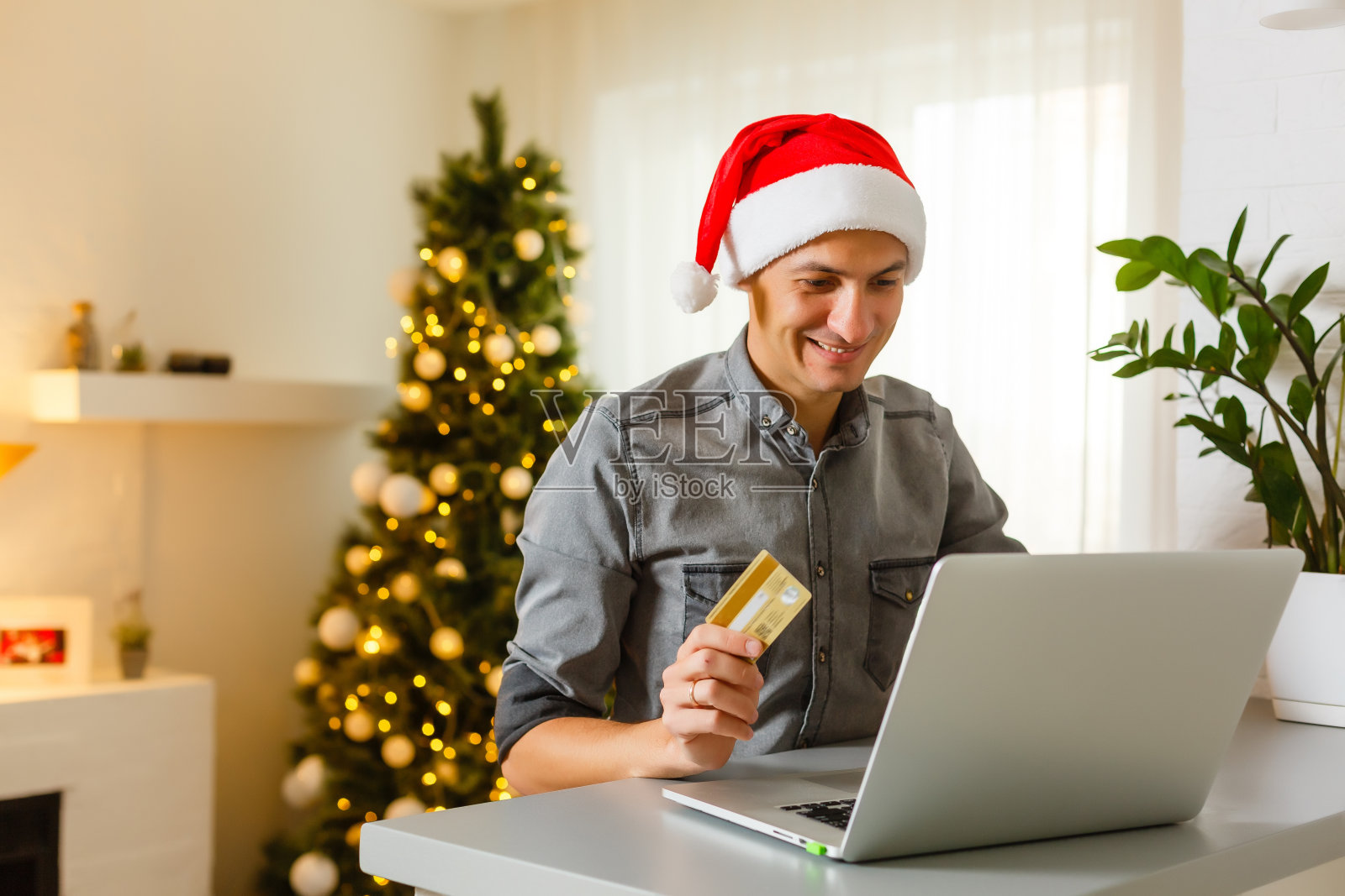 戴着圣诞老人帽的人拿着笔记本电脑，用快乐的圣诞打字照片摄影图片