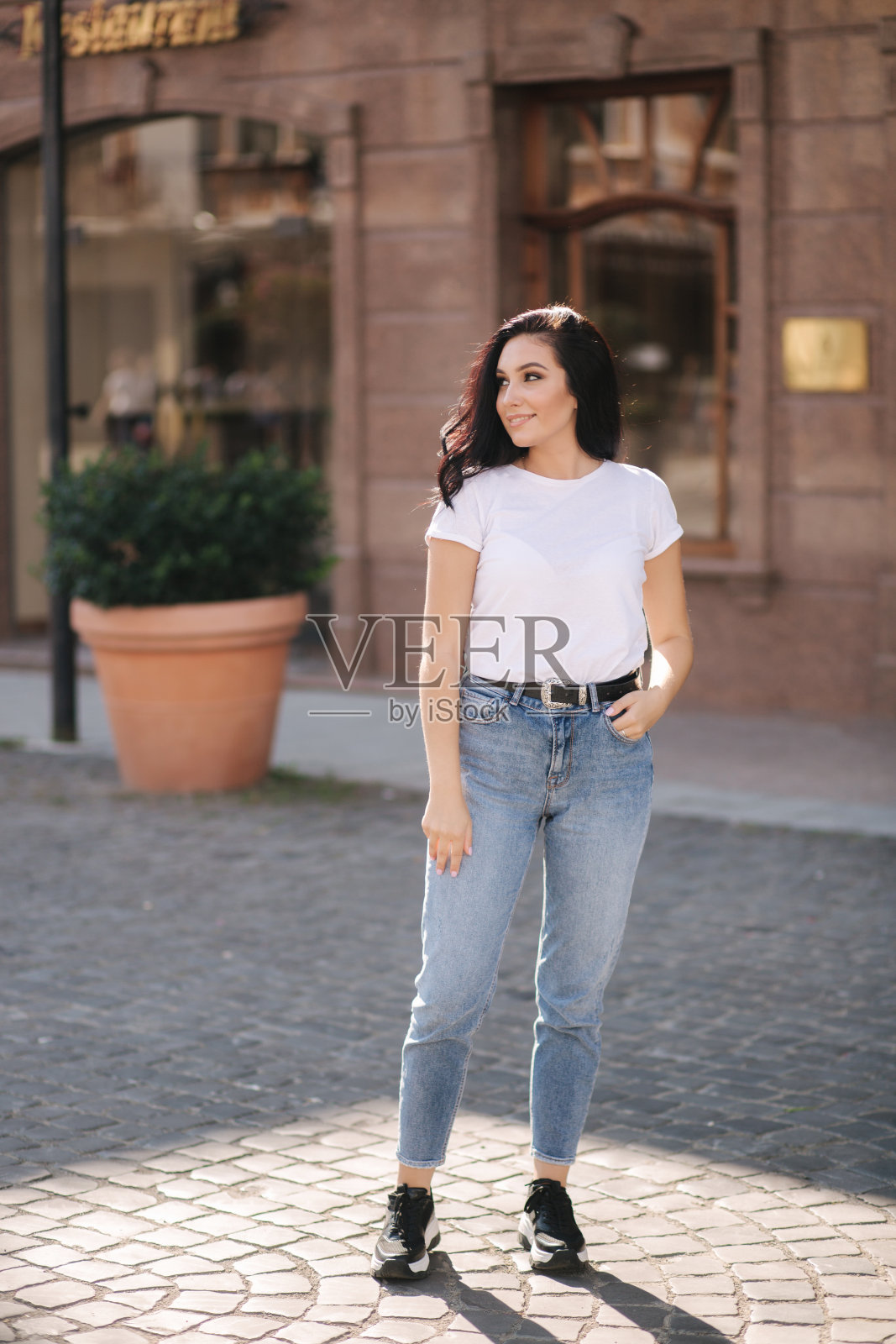 漂亮的年轻女子穿着白衬衫和牛仔裤走在城市里照片摄影图片