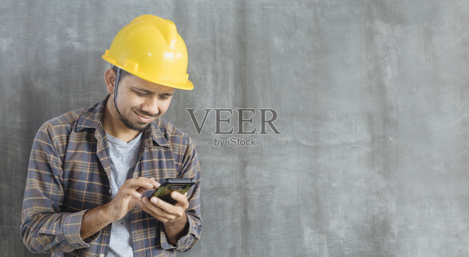 建筑工人使用智能手机在水泥墙的背景与复制空间照片摄影图片