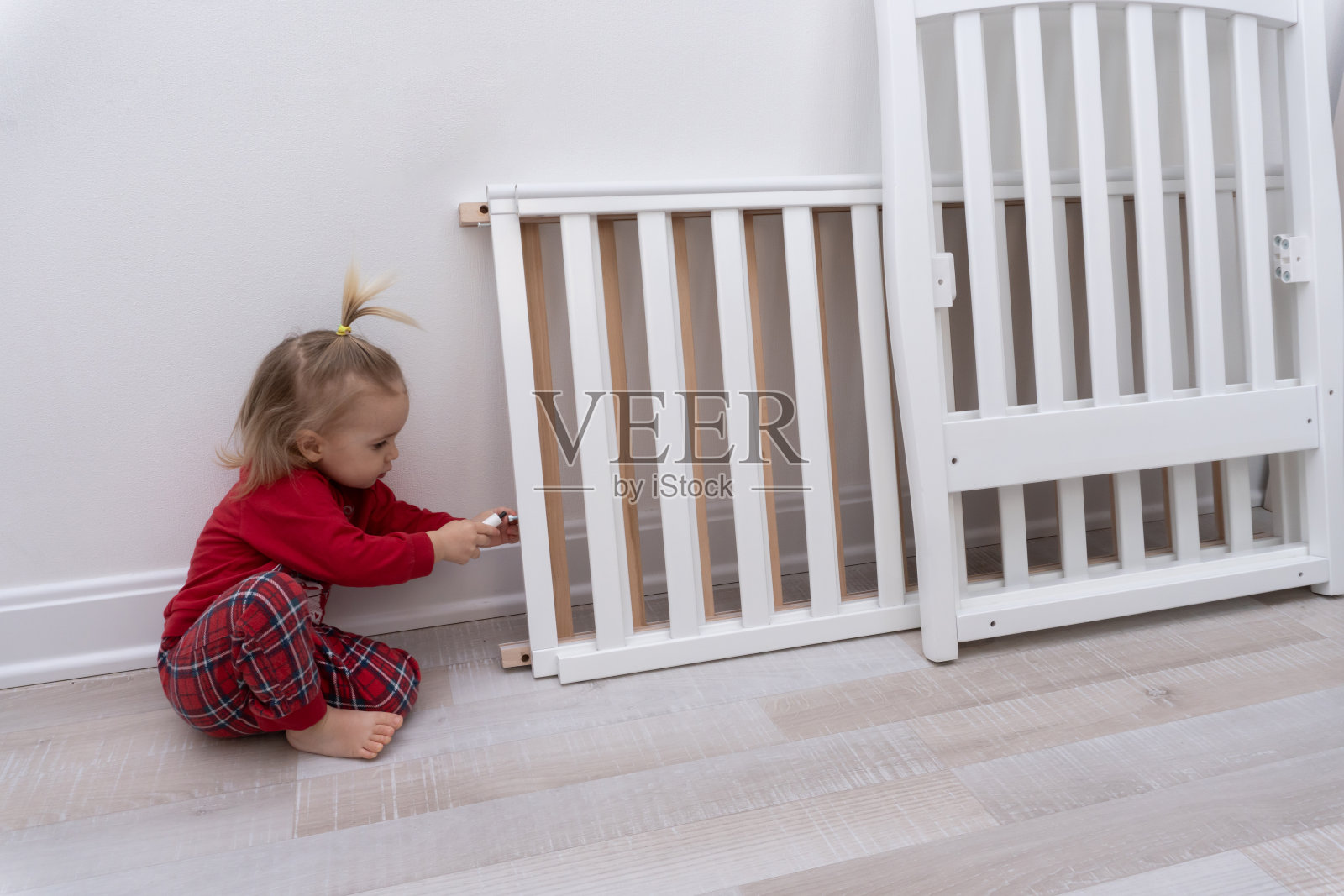 在白色墙壁的白色房间里，小朋友试图用螺丝刀组装儿童床。照片摄影图片