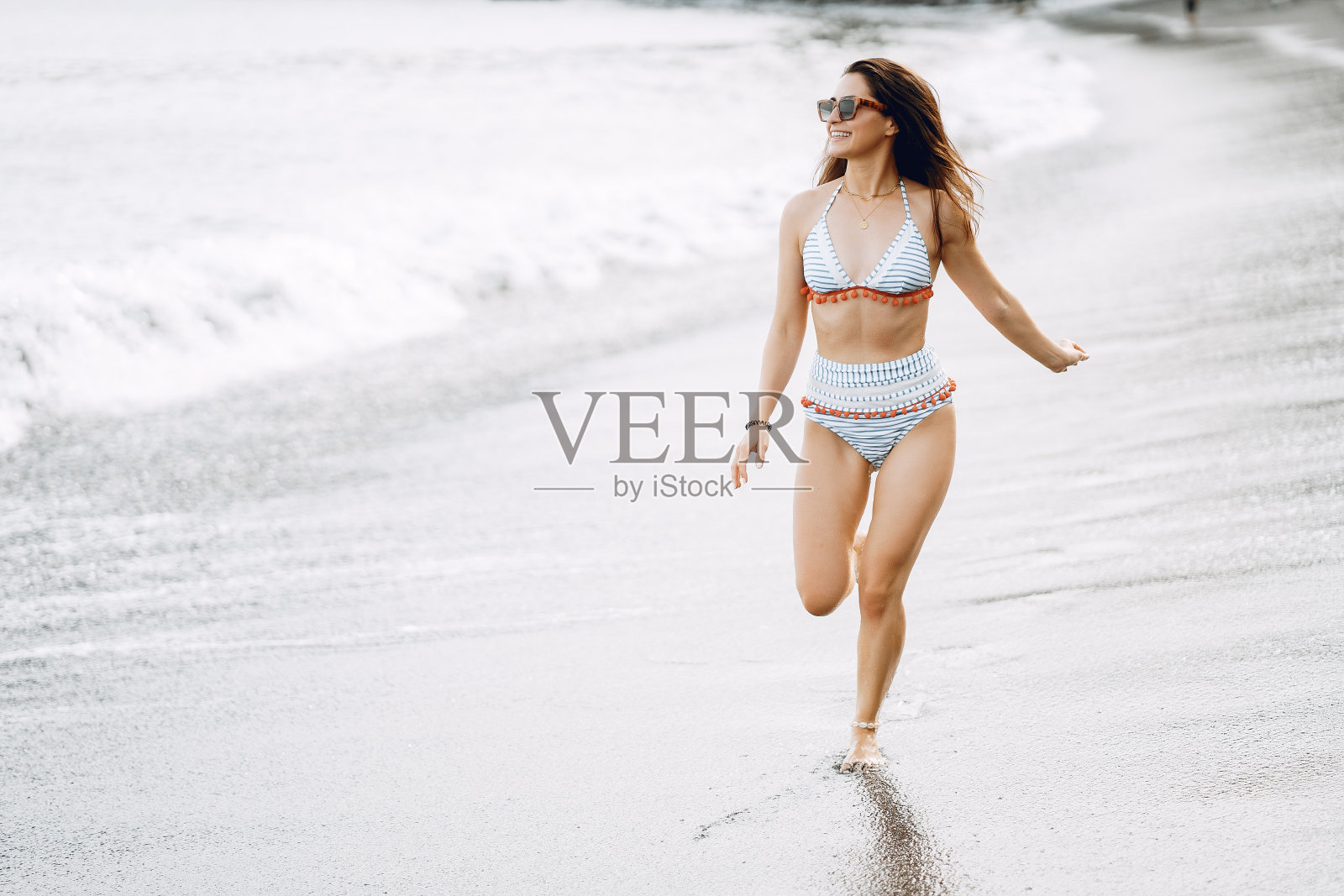 穿着时尚泳衣的女孩在海滩上休息照片摄影图片