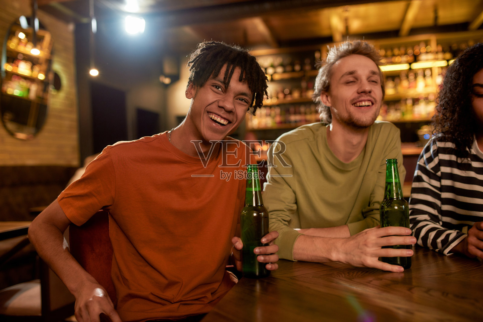 朋友们在酒吧里一起看电视上的体育比赛，喝啤酒，为球队加油。人、休闲、友谊、娱乐的理念照片摄影图片