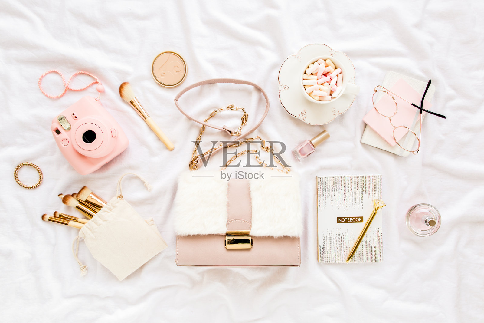 粉色手袋，相机，化妆刷，化妆品，太阳镜，白色背景的配件。平面构成。社交媒体。前视图。平躺照片摄影图片