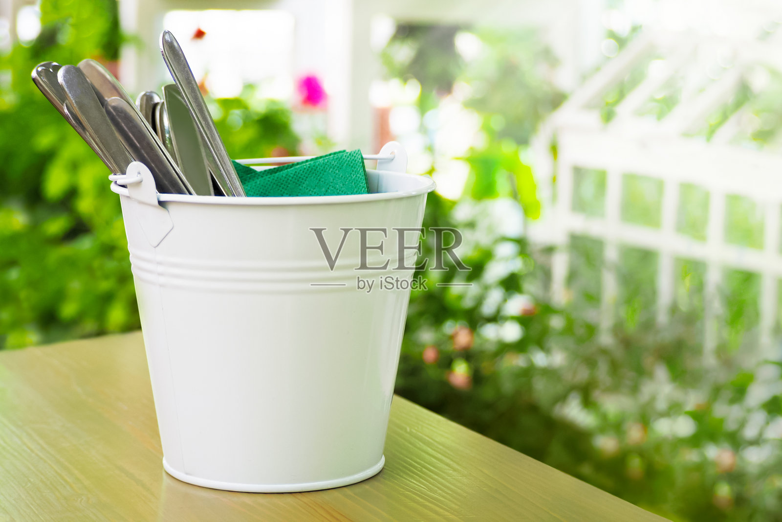 在绿色花园的桌子上，一桶餐具。绿色食品理念，温室效应照片摄影图片