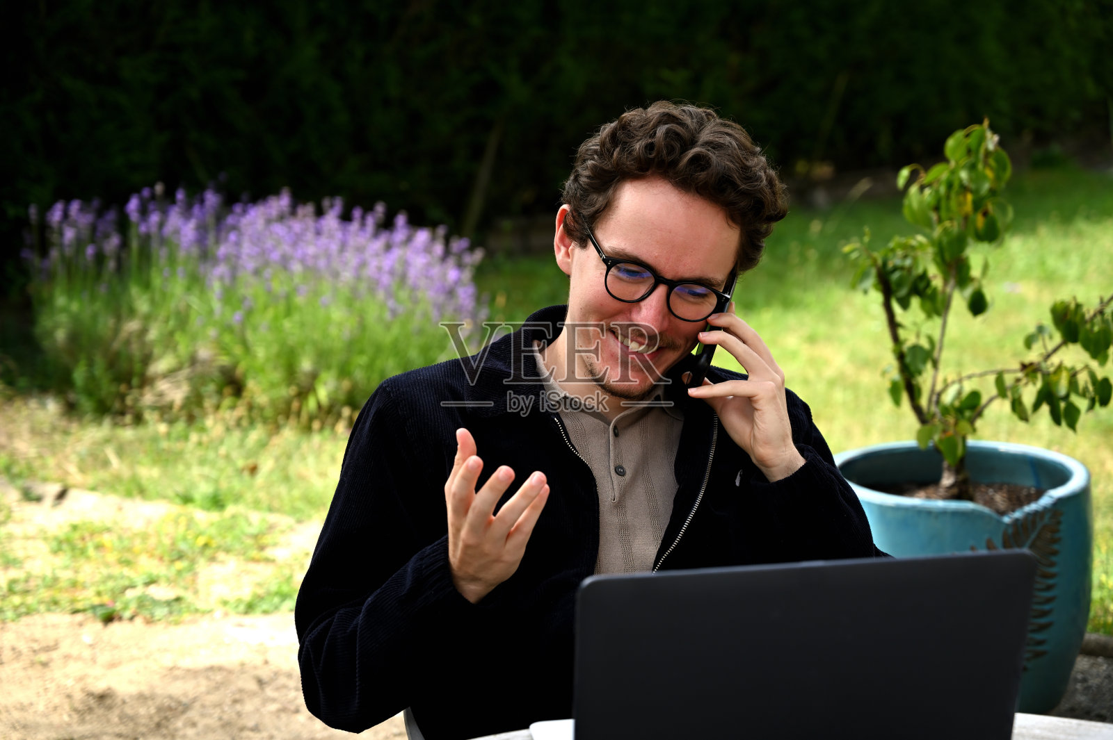 家庭办公室。年轻人在家工作，在花园里打电话照片摄影图片