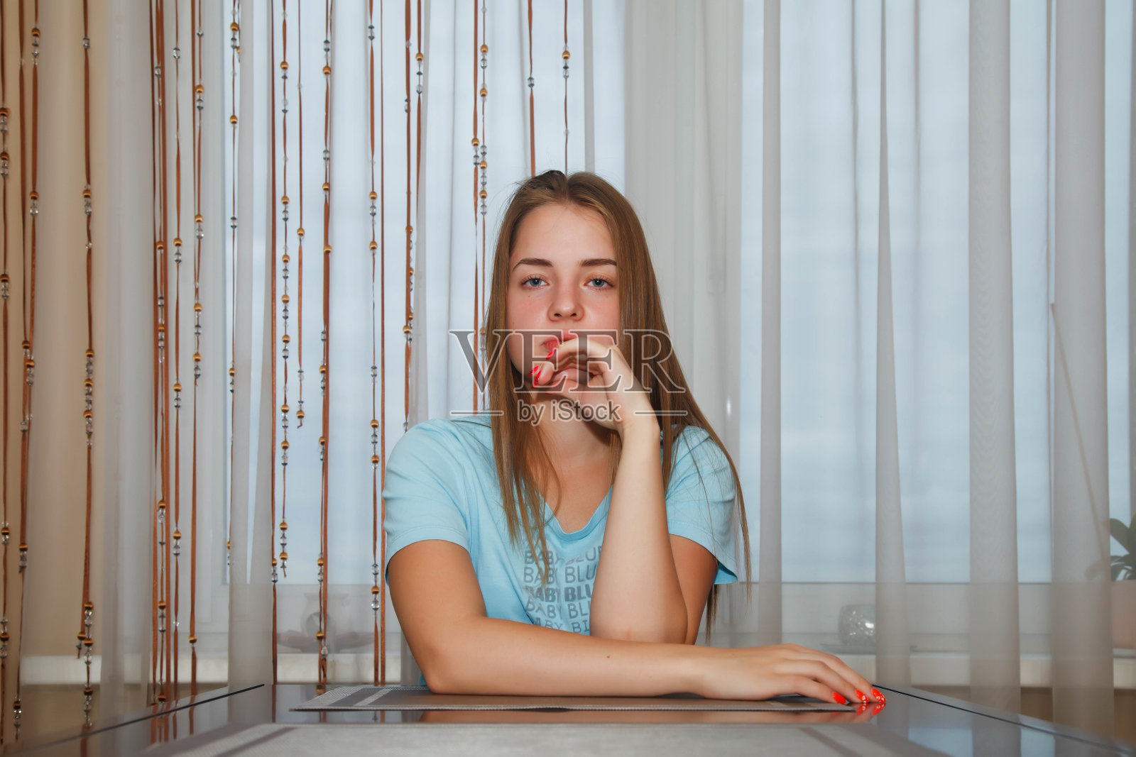 坐在窗边桌旁的悲伤漂亮少女照片摄影图片