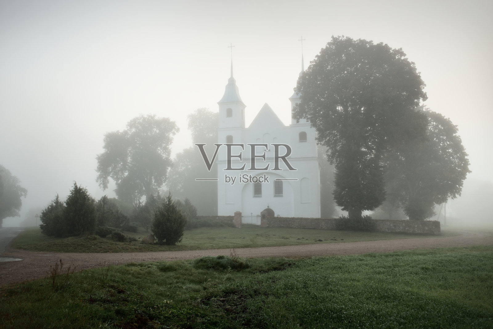 一个古老的白色传统天主教堂在一层厚厚的神秘的雾中，特写。旅游目的地，观光，国家地标，文化和宗教，天主教，基督教，过去，建筑照片摄影图片
