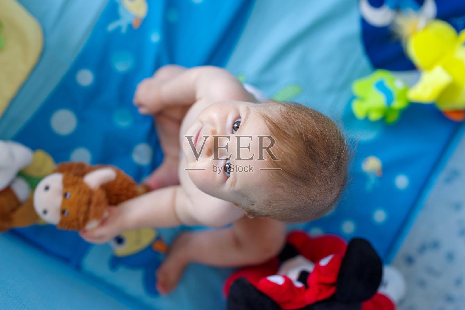 婴儿围栏里的小女孩抬头看照片摄影图片