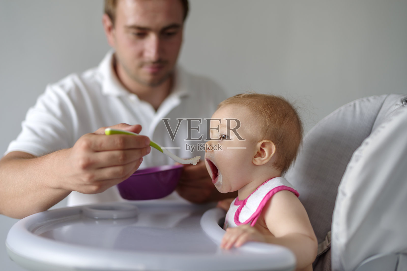 父亲在高椅子上给女儿喂奶照片摄影图片