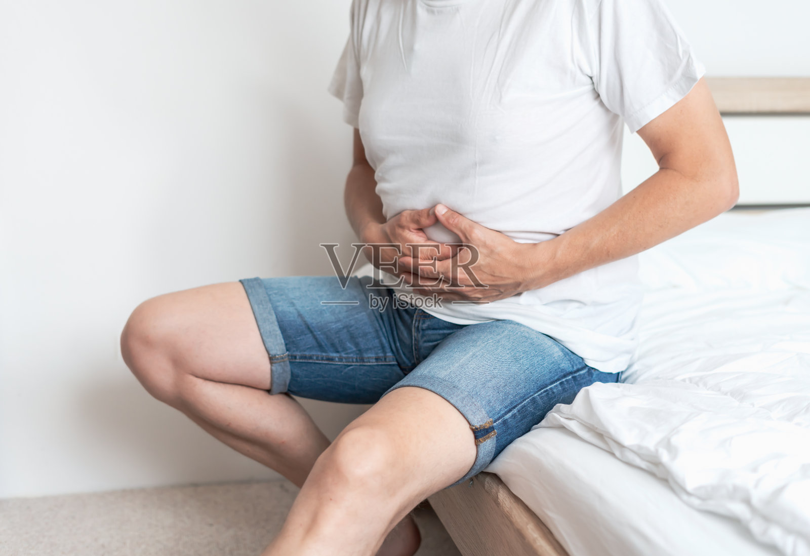 一个胃痛的男人坐在床上照片摄影图片