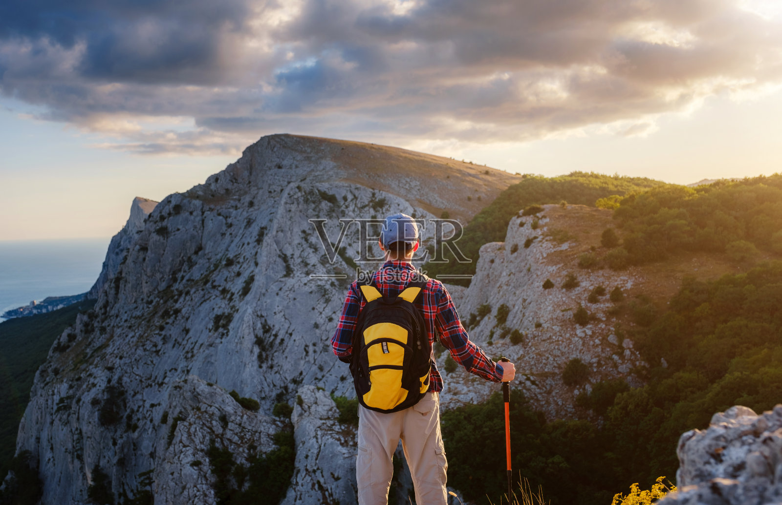 一个爱冒险的人站在山顶上，欣赏着日落时分的美景照片摄影图片