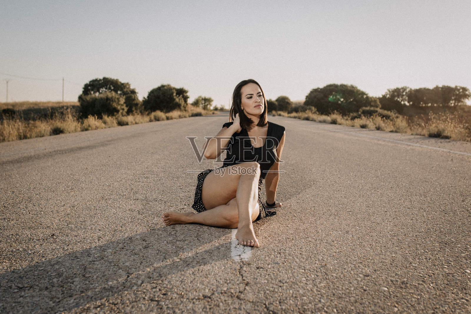 一个穿黑衣服的女人坐在空旷的路上照片摄影图片