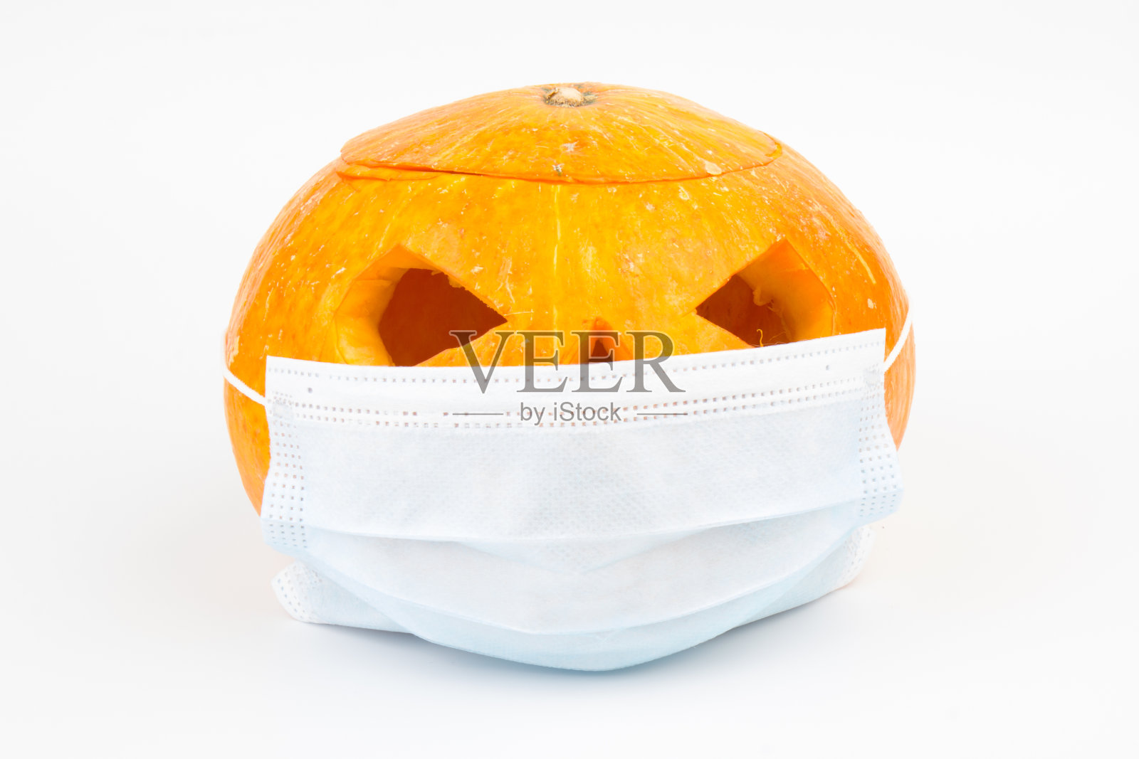 万圣节面具是一个南瓜灯，南瓜戴着医用面具，象征着疾病控制和病毒感染，以及冠状病毒或新冠病毒的安全照片摄影图片