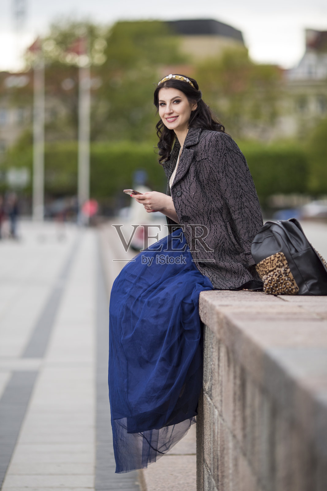 美丽微笑的女人在户外用手机的肖像。垂直的图像照片摄影图片
