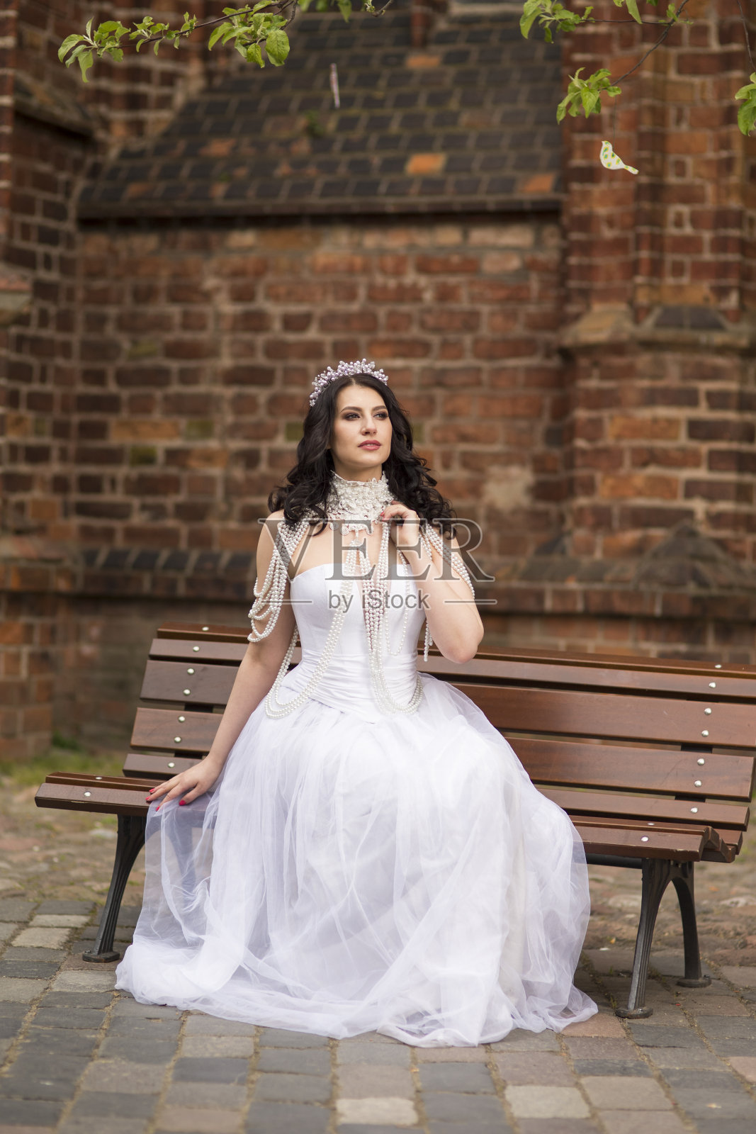 画像的白人黑发新娘与头冠和项链。在城堡院子里摆姿势。垂直组成照片摄影图片