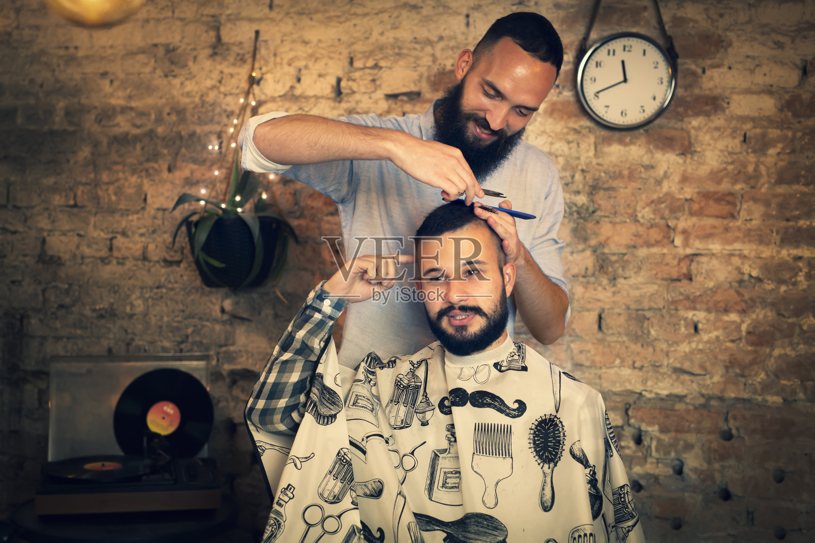 帅哥在理发店。理发师剪了他的头发，修剪了他的胡子。照片摄影图片