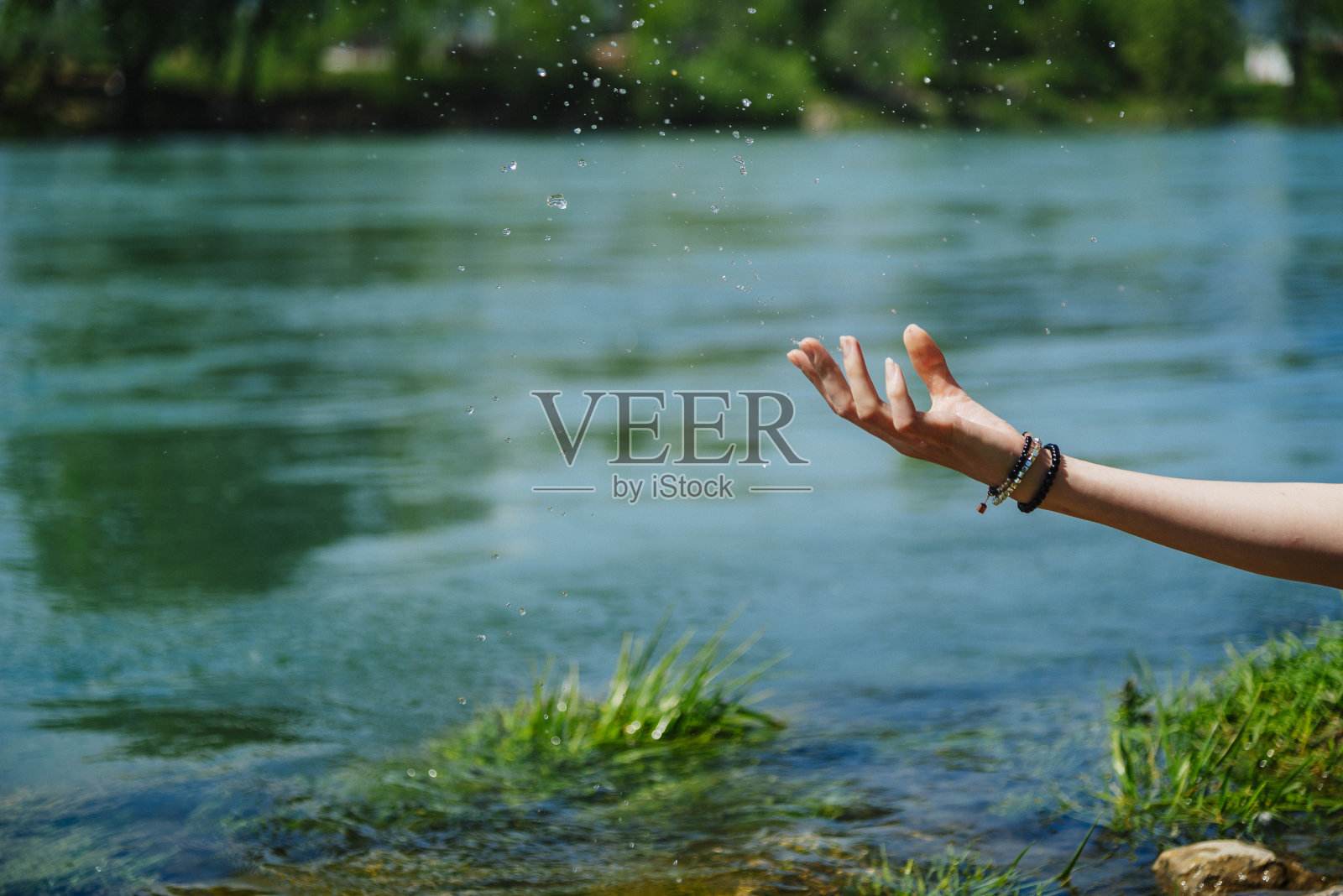 年轻美丽的女子抚摸着水面，享受着在大自然中独处的一天照片摄影图片