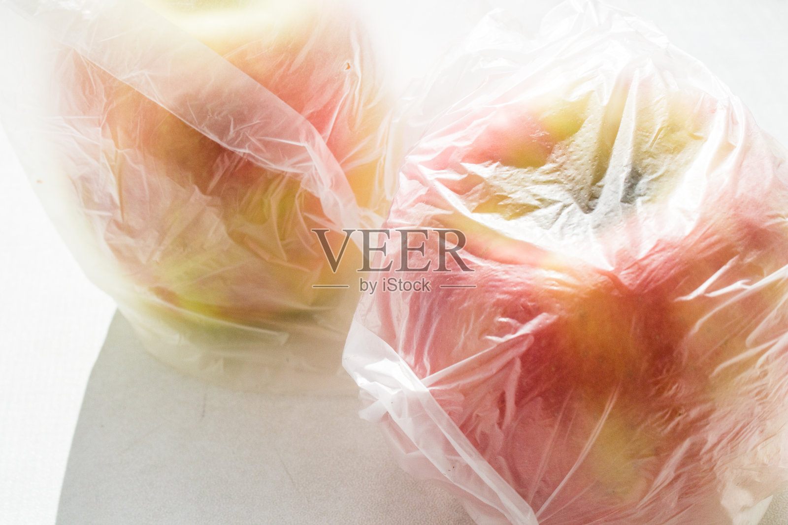 红色和黄色的苹果装在一个塑料袋里。照片摄影图片