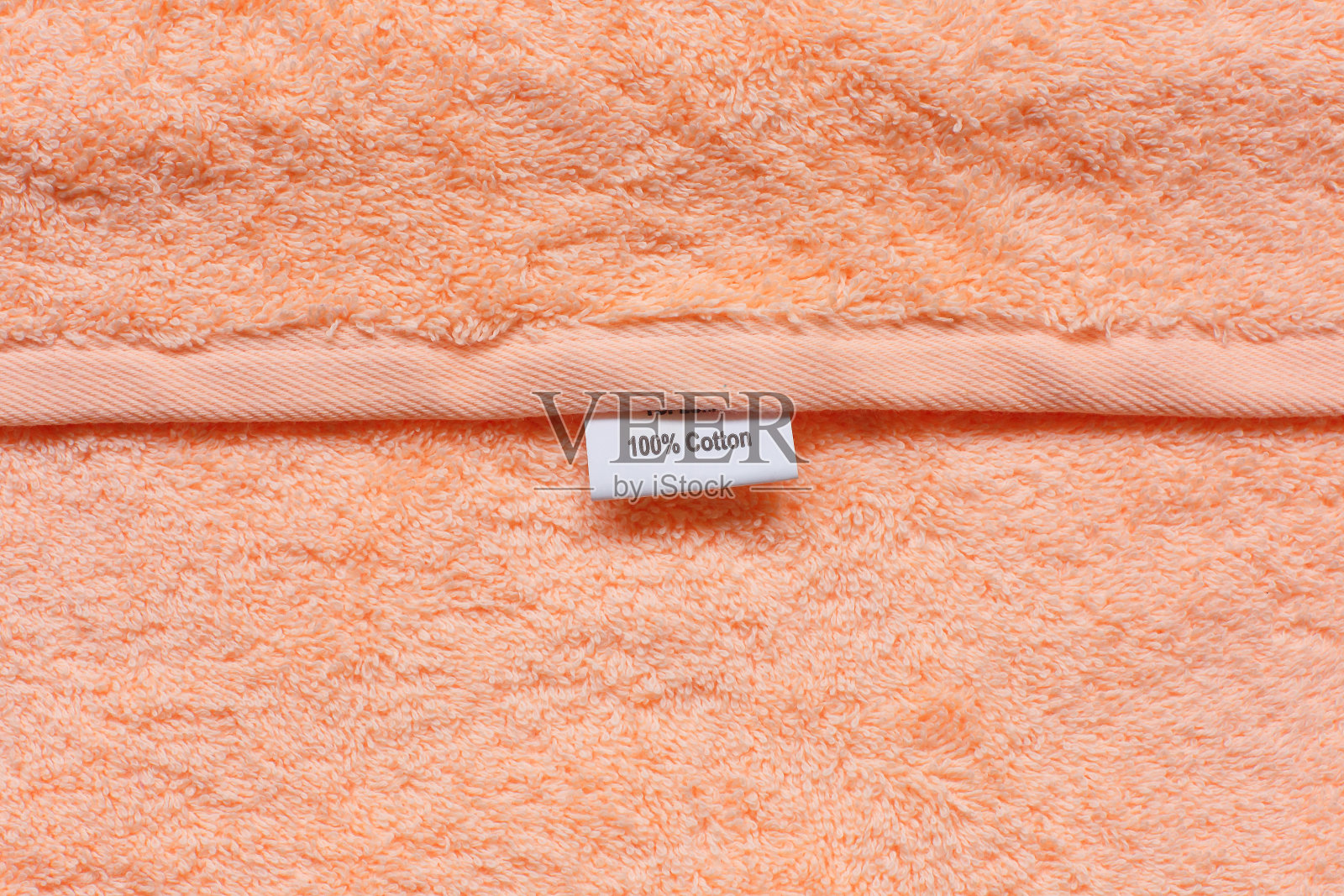 质地柔软的桃色织物与标签的100%棉花。照片摄影图片
