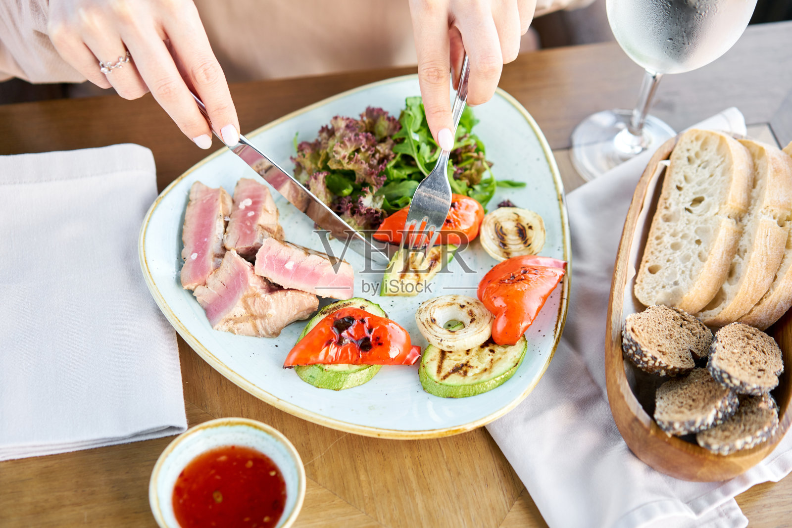 女人吃半熟的金枪鱼配生菜和辣酱。在咖啡馆吃午餐。餐厅的菜单照片摄影图片