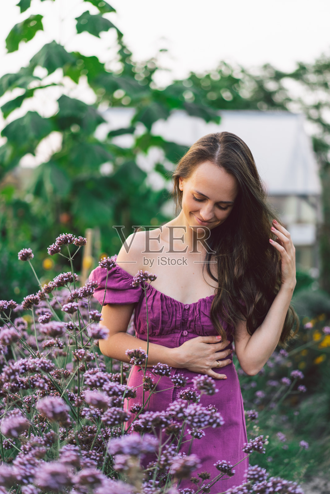 画着紫色花朵的长发女孩。在花园里散步。女孩和花照片摄影图片