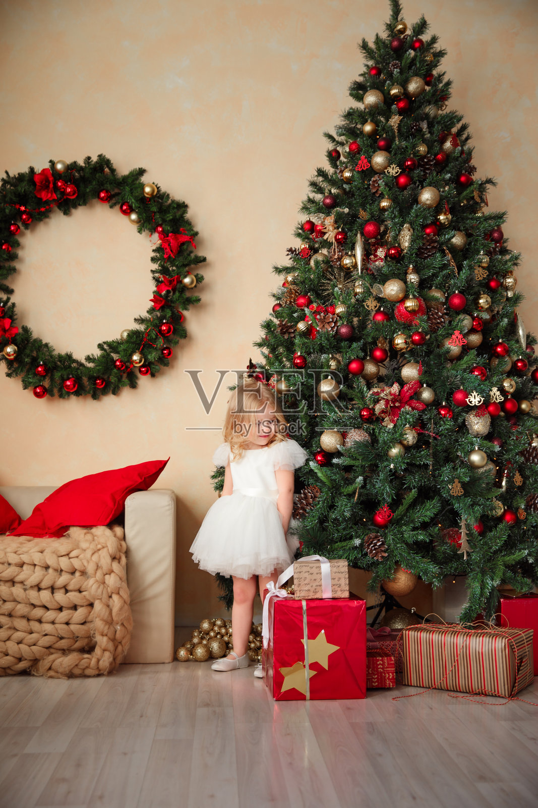 女孩在圣诞树和迷你房子附近。照片摄影图片