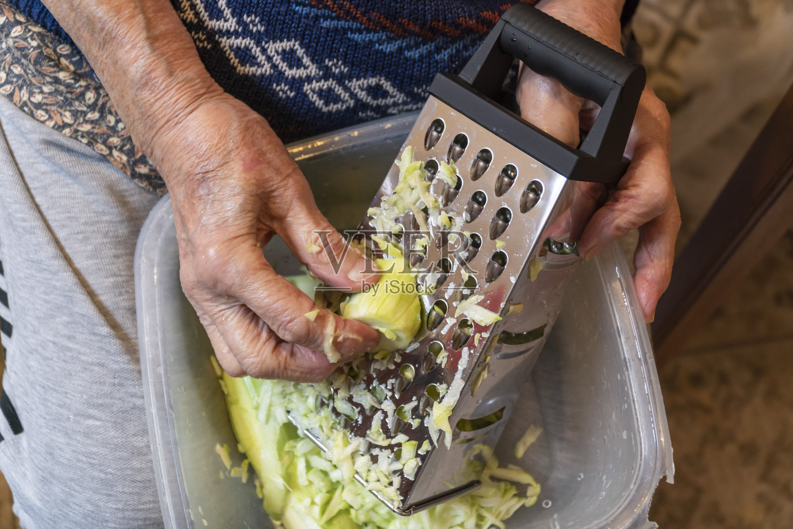皱巴巴的手在厨房里磨西葫芦照片摄影图片