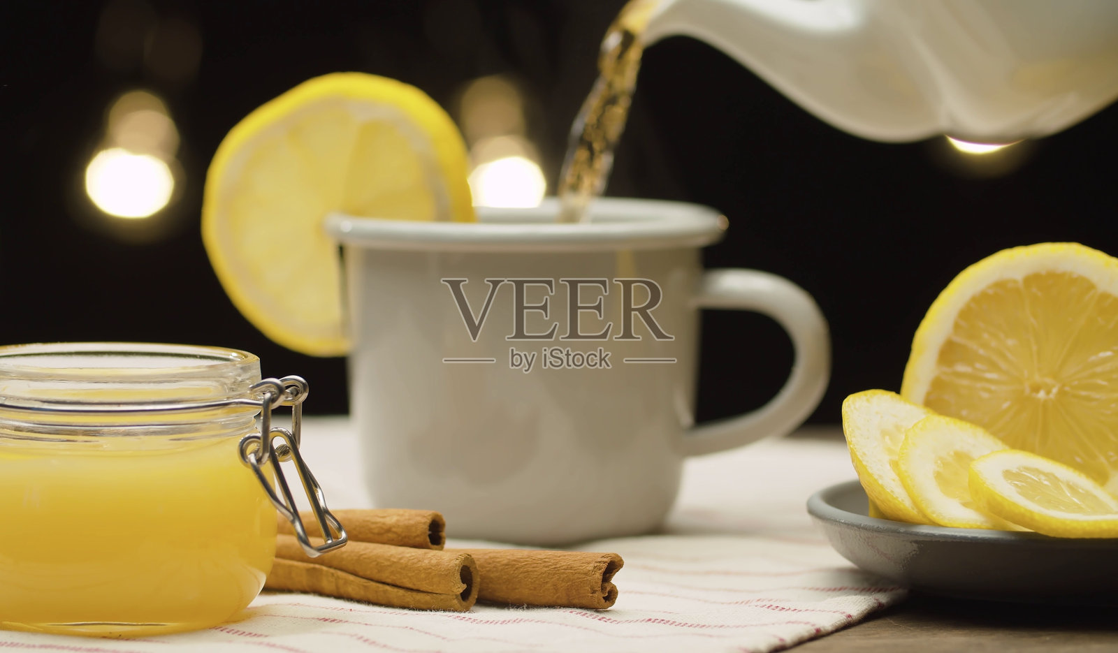 将茶倒入杯中，加入柠檬和肉桂照片摄影图片
