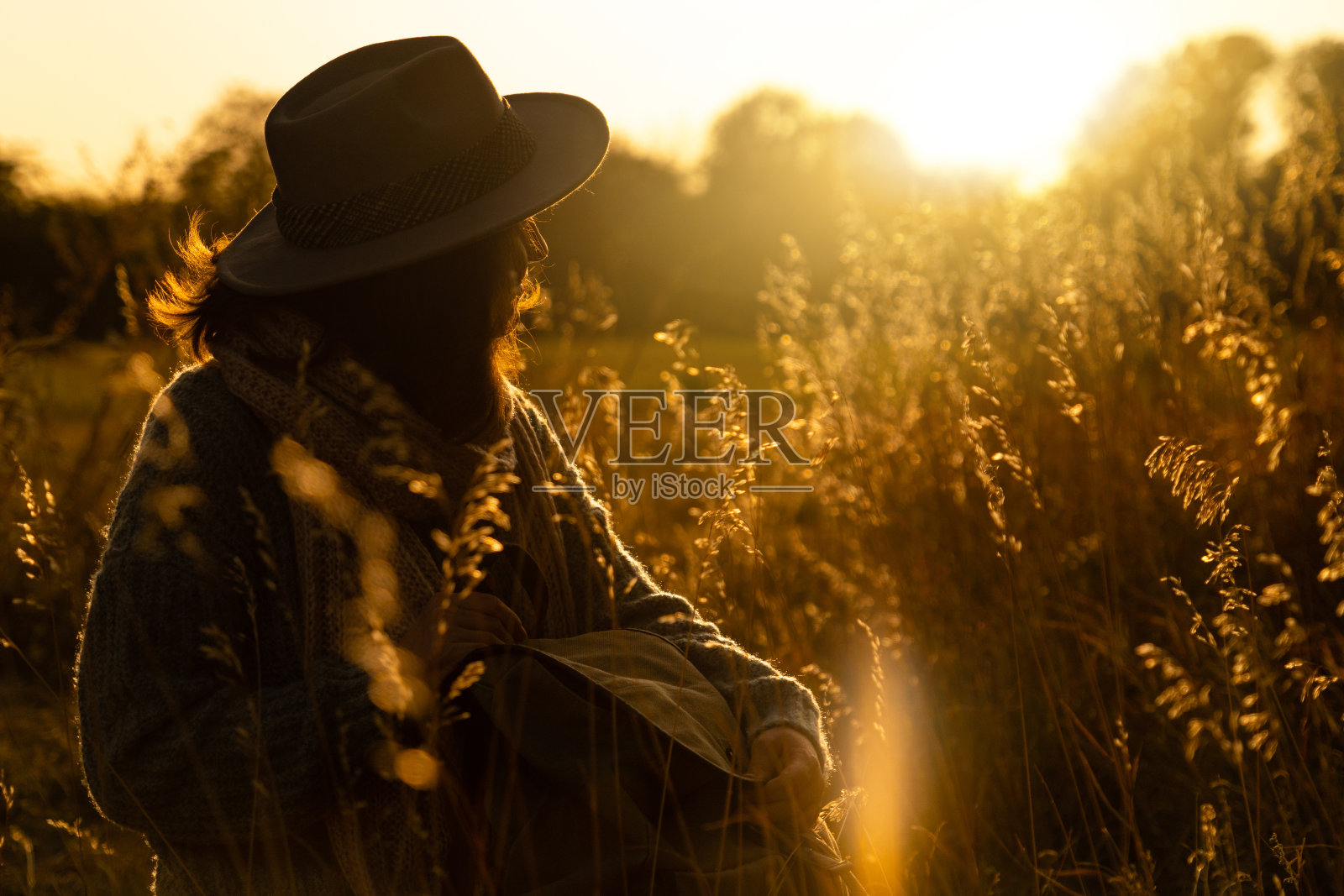 一个戴着帽子，背着背包的女人在日落时的肖像。照片摄影图片