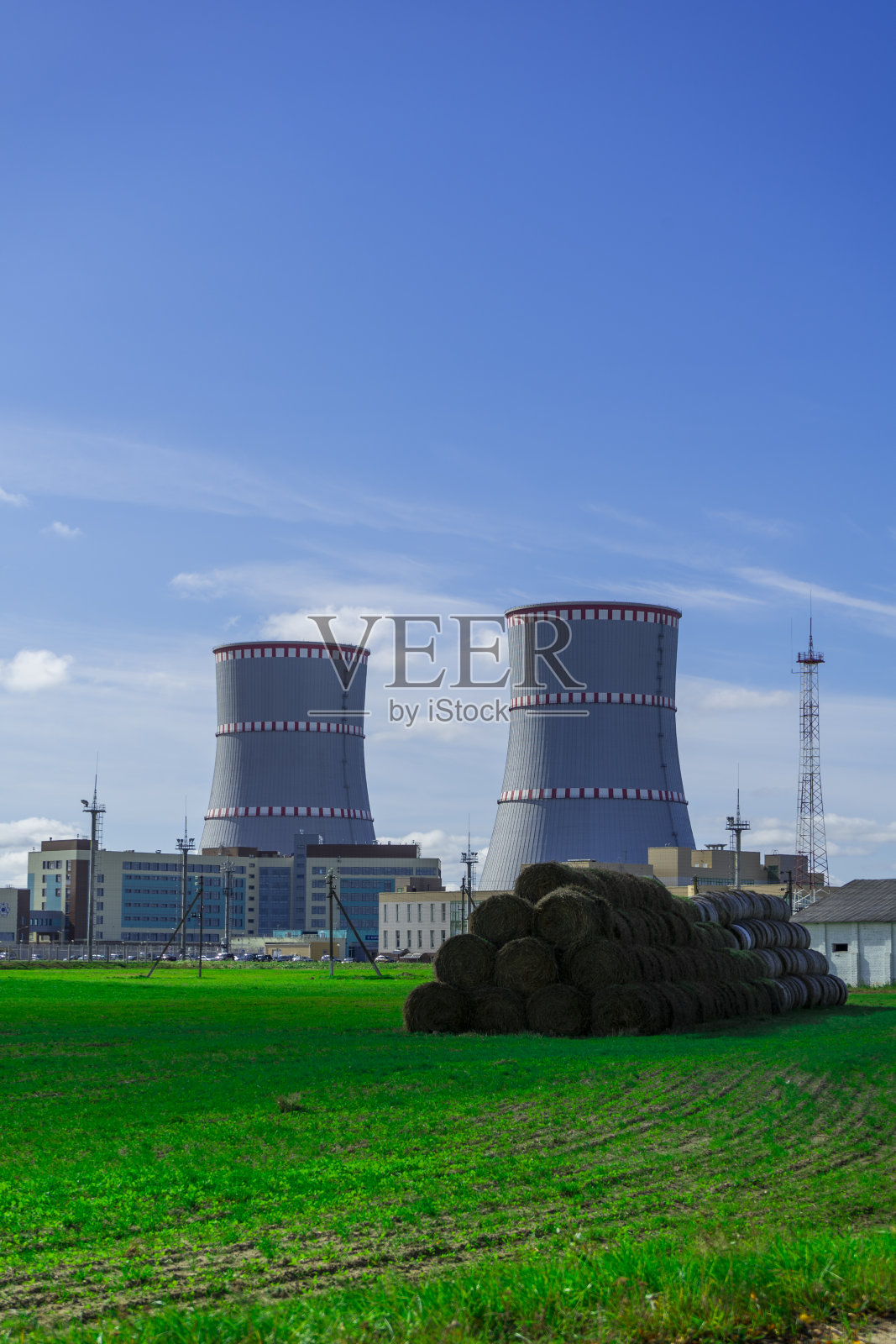 白俄罗斯核电站。以核电站为背景的绿色田野和草堆。照片摄影图片