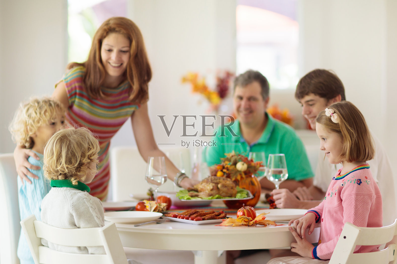 全家带着孩子吃感恩节晚餐。火鸡照片摄影图片