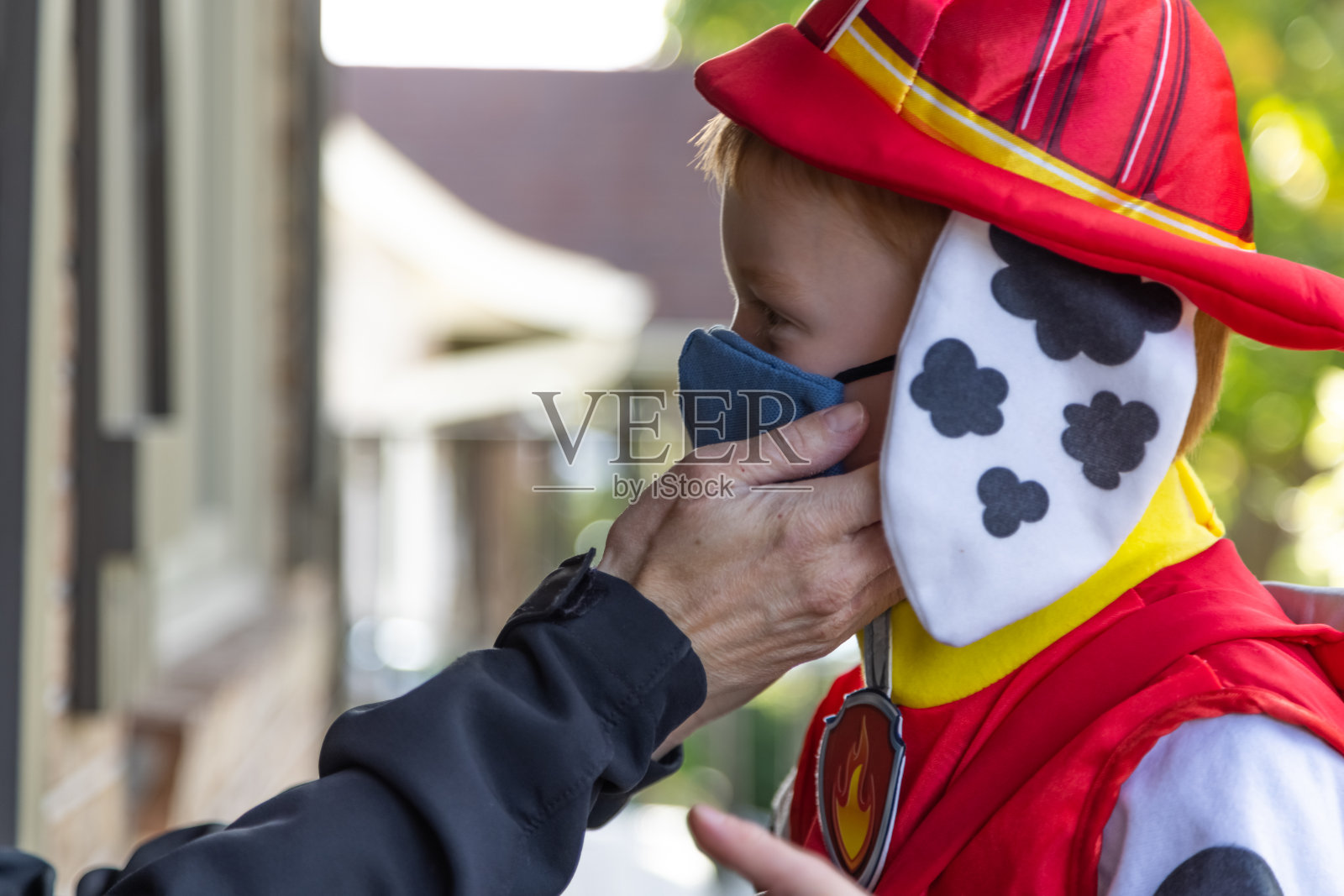 万圣节期间，母亲为孩子戴上防护口罩，预防新冠疫情照片摄影图片