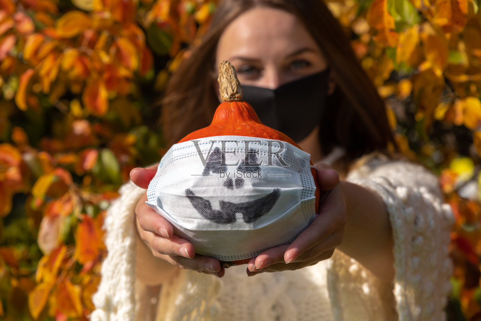 一个女人手上戴着医用面具的南瓜照片摄影图片
