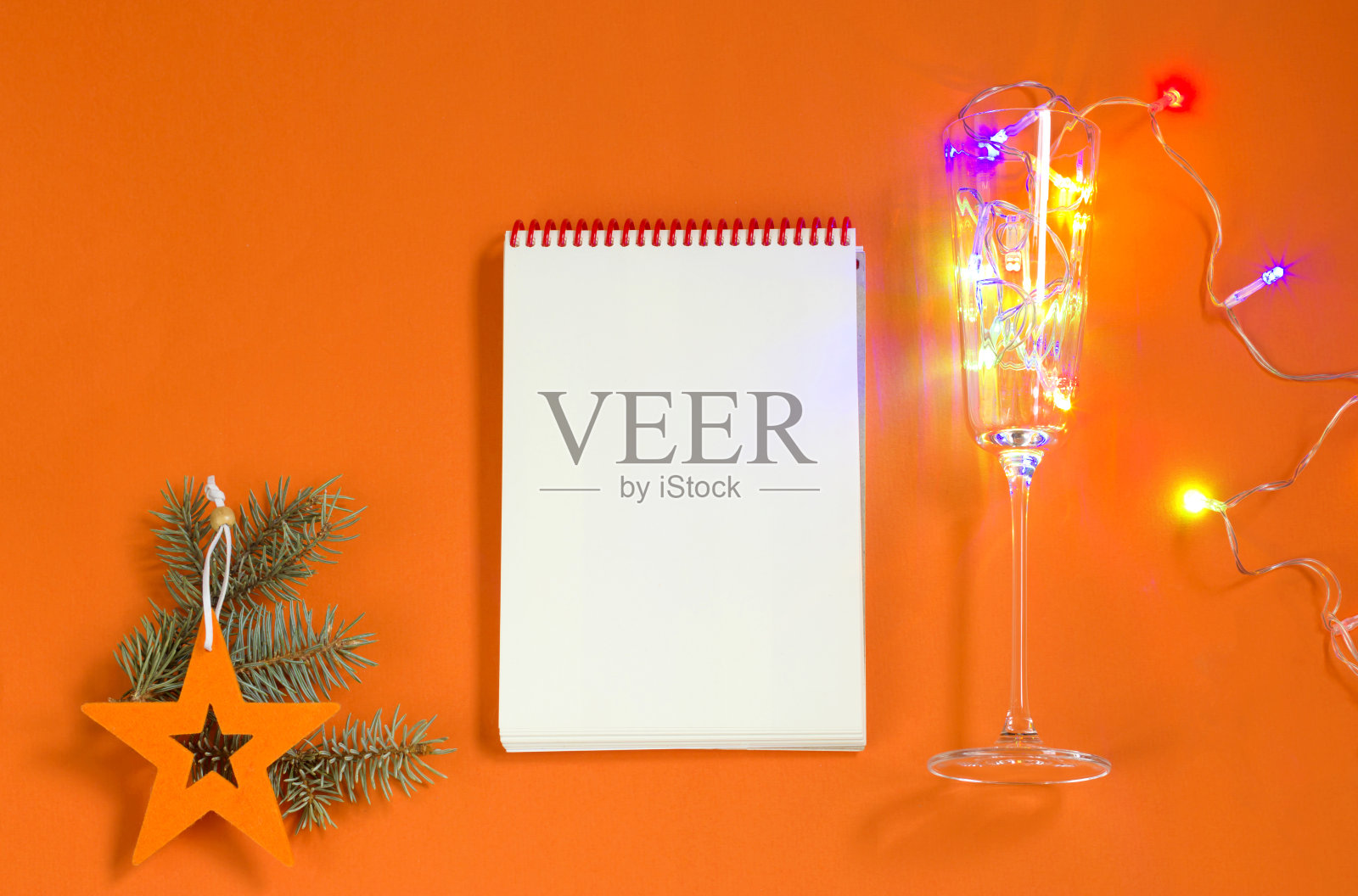 写下来年目标或计划的笔记本。圣诞玩具，橙色背景的花环。新年的概念。平躺，俯视，生活方式。副本的空间。照片摄影图片