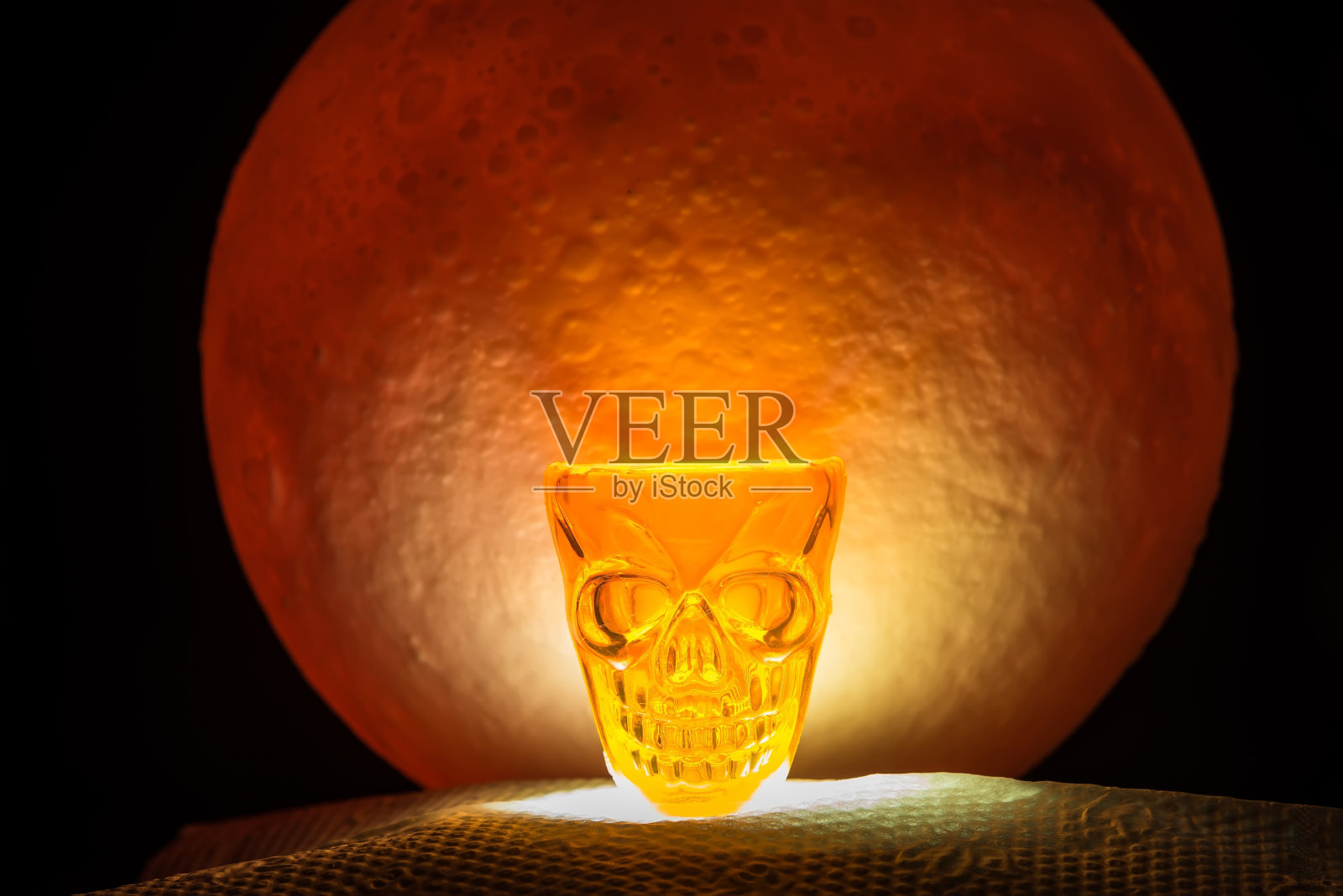 万圣节用的骷髅玻璃。背景中有一轮红色的满月。万圣节恐怖的概念。照片摄影图片