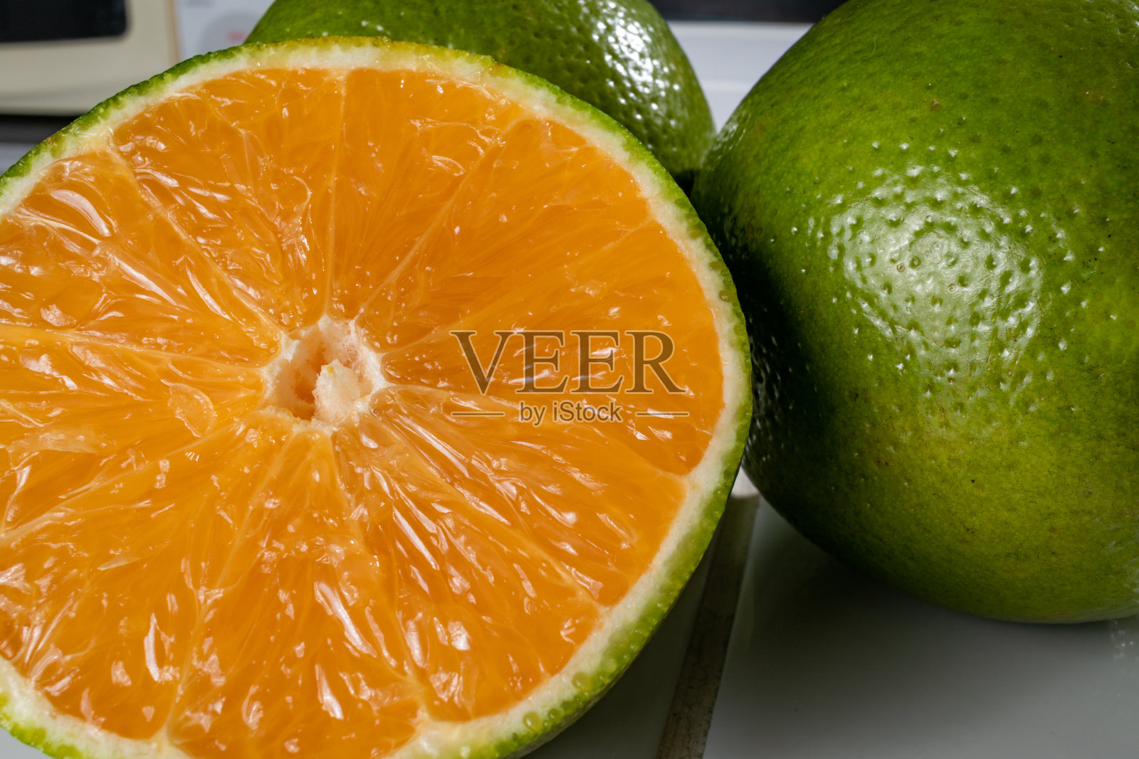 三个橙子，一切两整，放在白色瓷砖上照片摄影图片