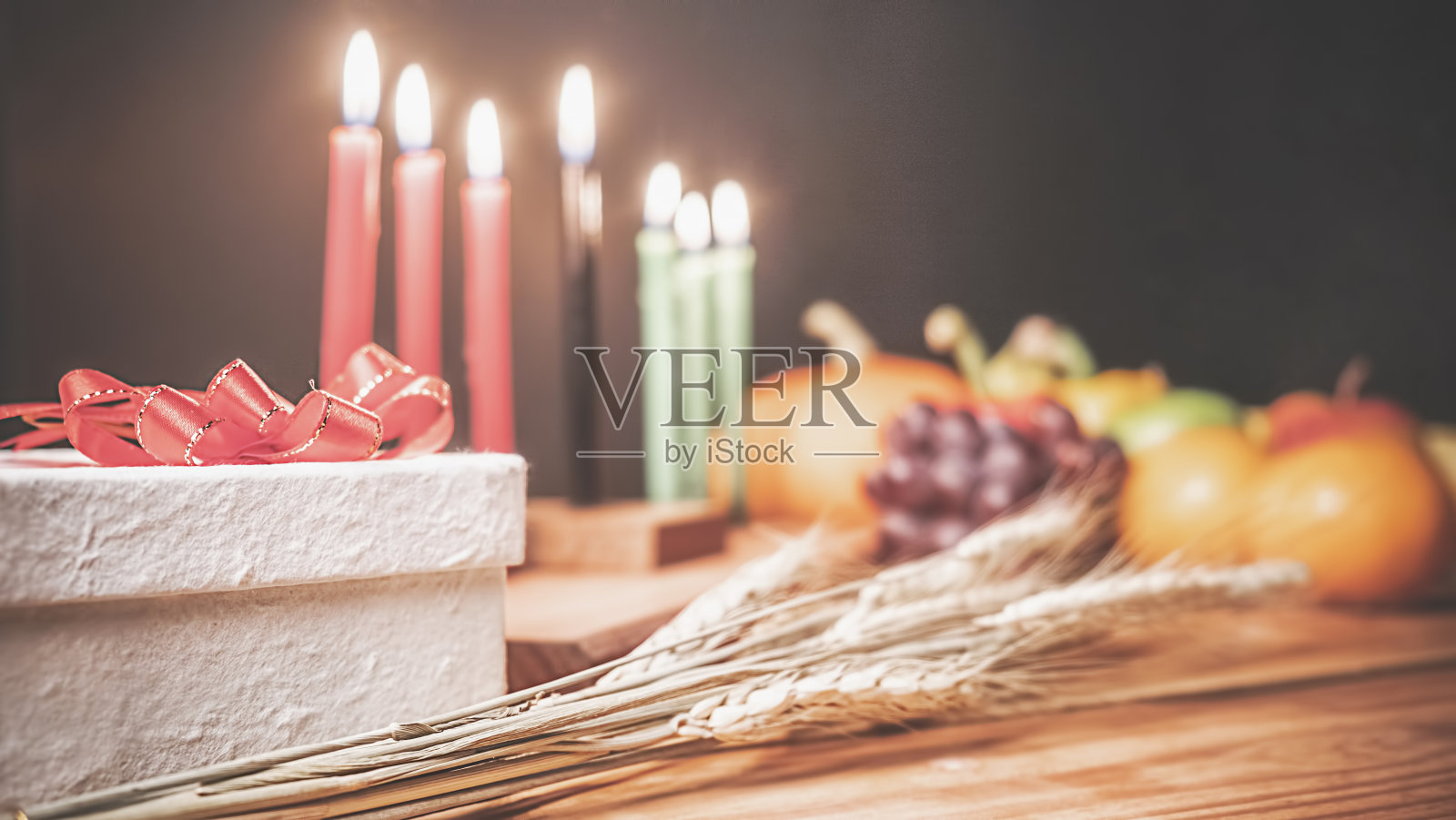 宽扎节的概念是用红、黑、绿三色的七支蜡烛、礼盒、南瓜、玉米和水果等装饰在木制的桌子和黑色的背景上。照片摄影图片