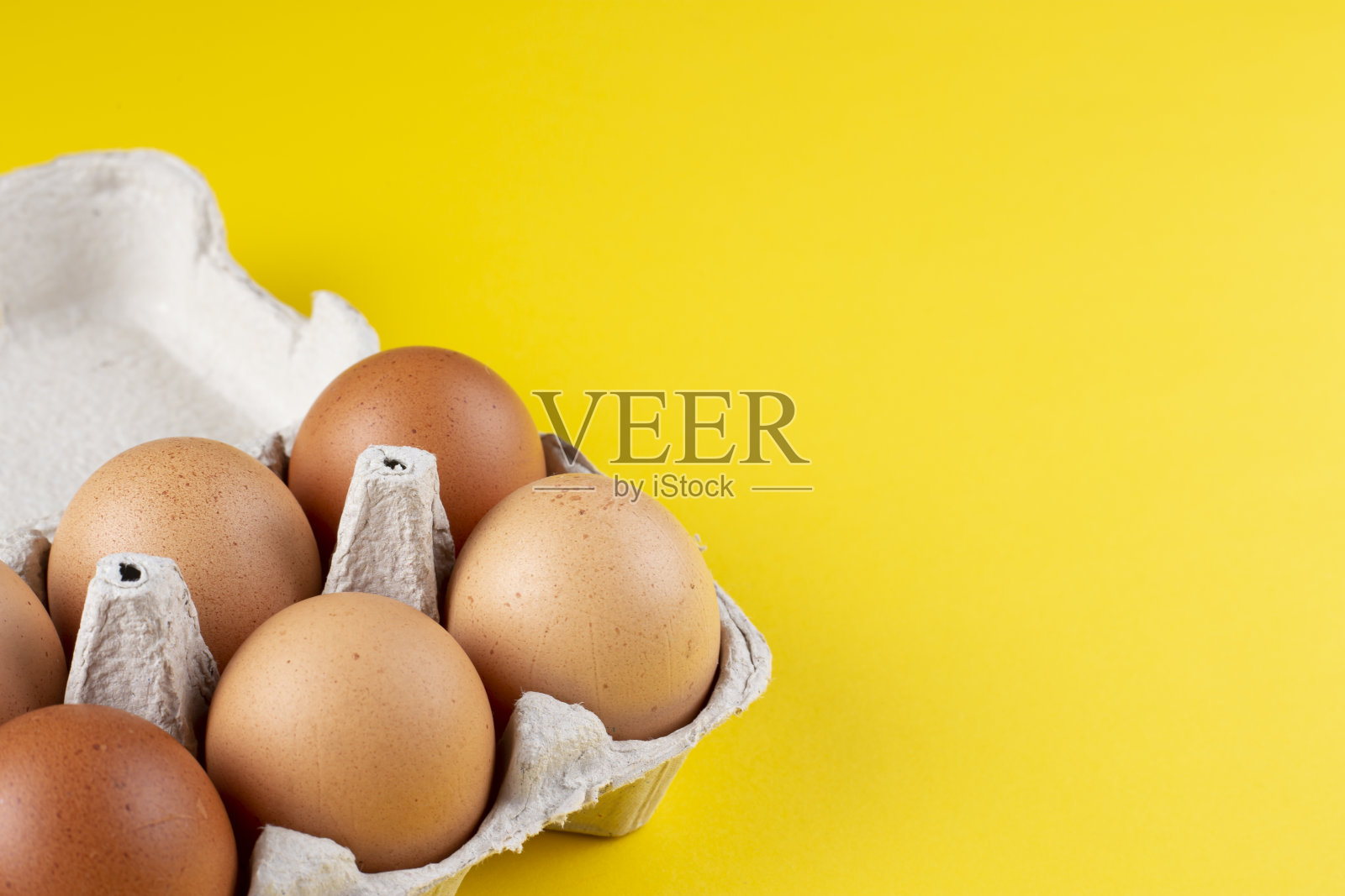 鸡蛋在打开的鸡蛋箱里孤立在黄色。顶部视图与复制空间。照片摄影图片