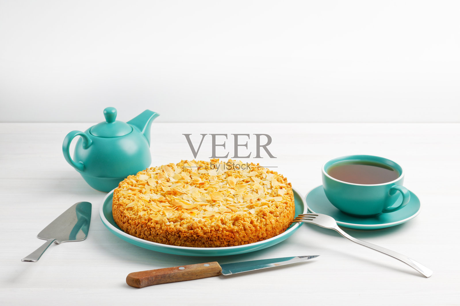 白色木桌上放着杏仁花瓣的苹果派和一杯茶。Copyspace。照片摄影图片