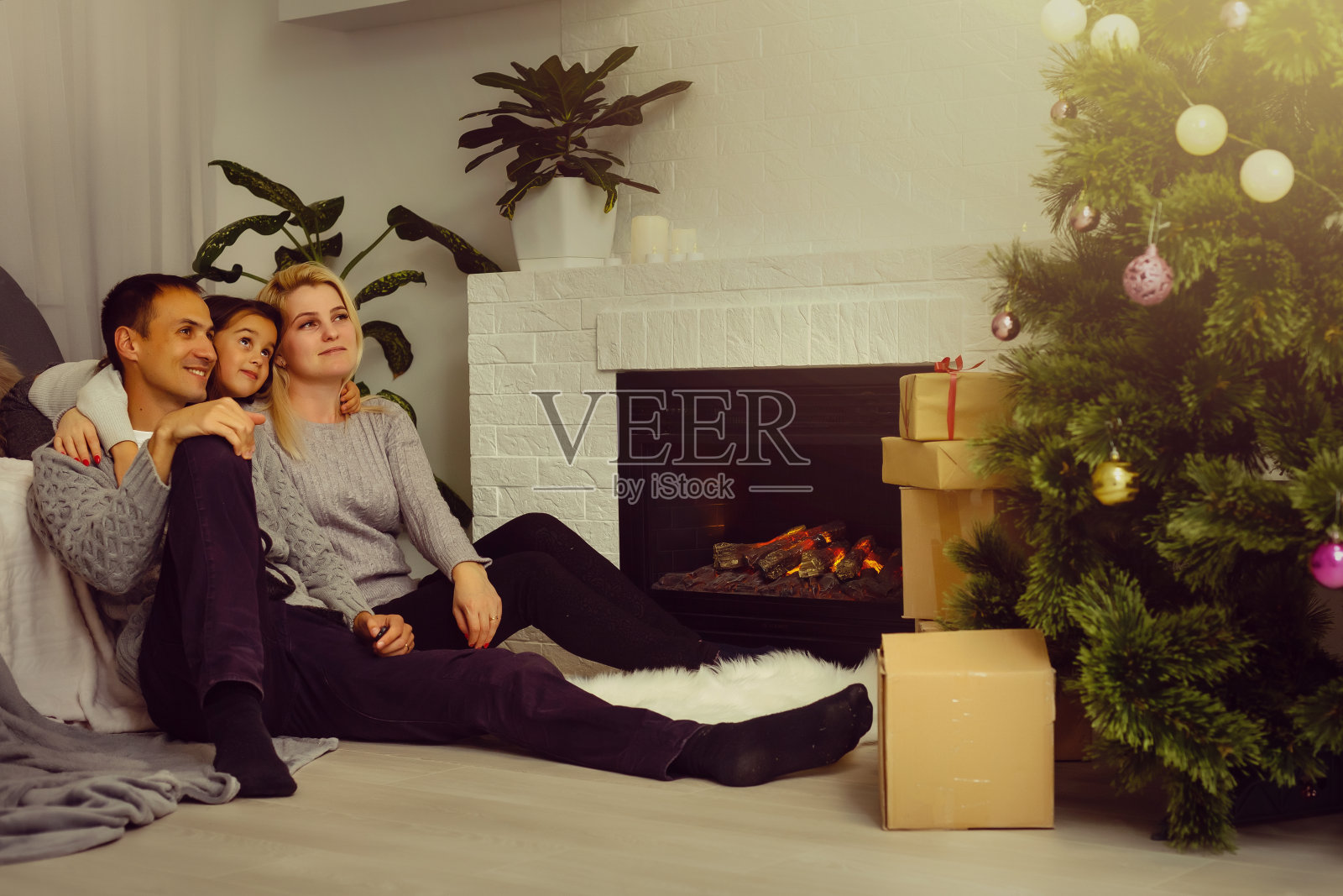 幸福的家庭，父亲，母亲和孩子们坐在壁炉旁的圣诞夜照片摄影图片