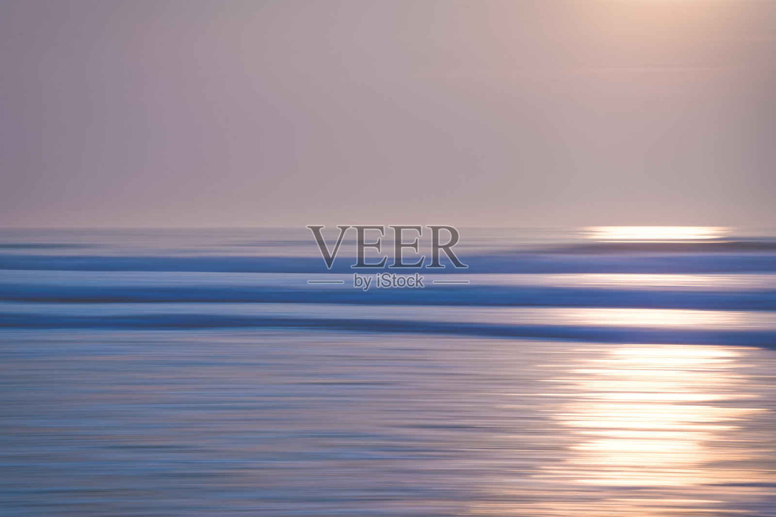 抽象海景与模糊平移运动。日出或日落在海上，美丽的浅蓝色和粉红色照片摄影图片