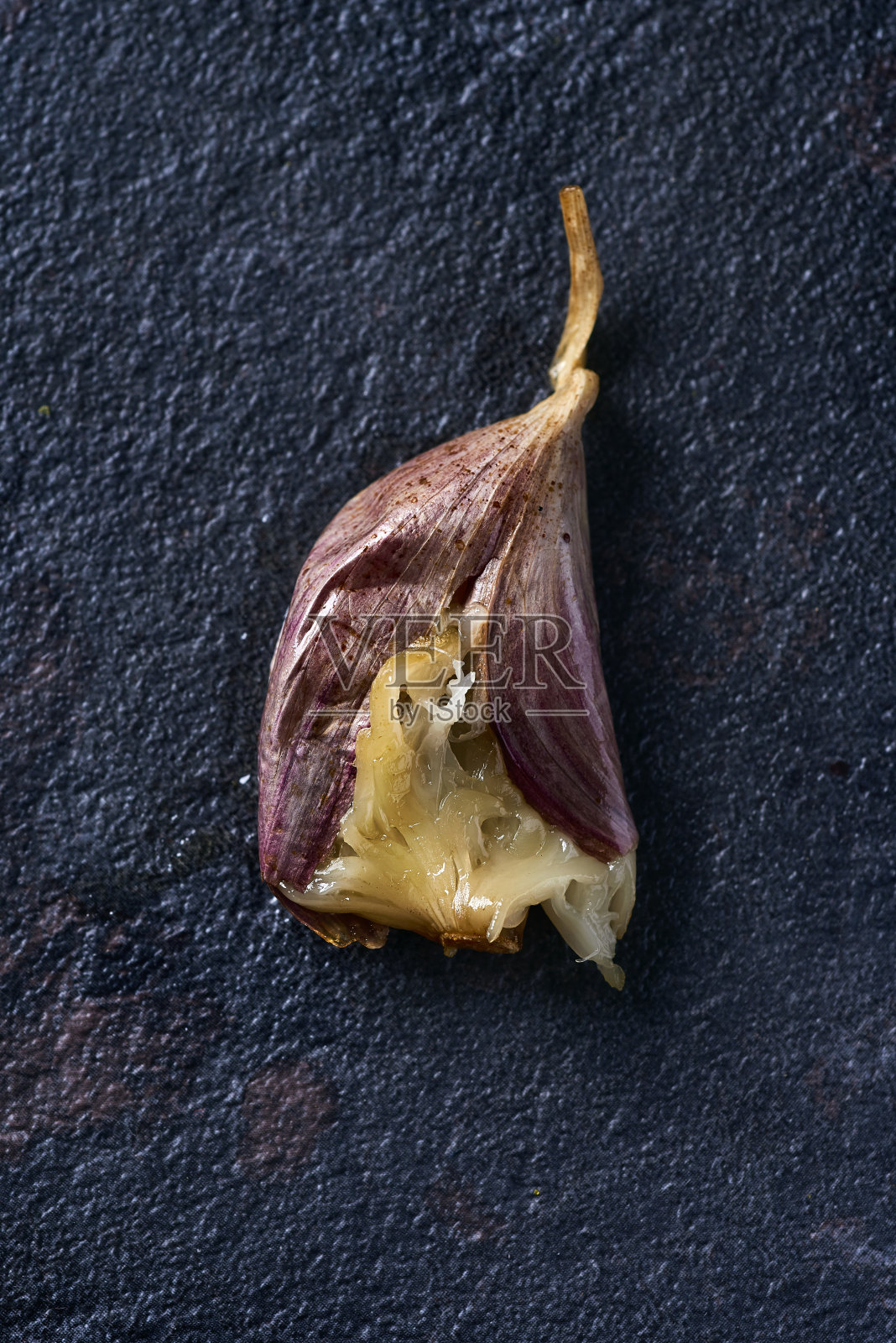 烤蒜瓣在黑色的石头表面照片摄影图片