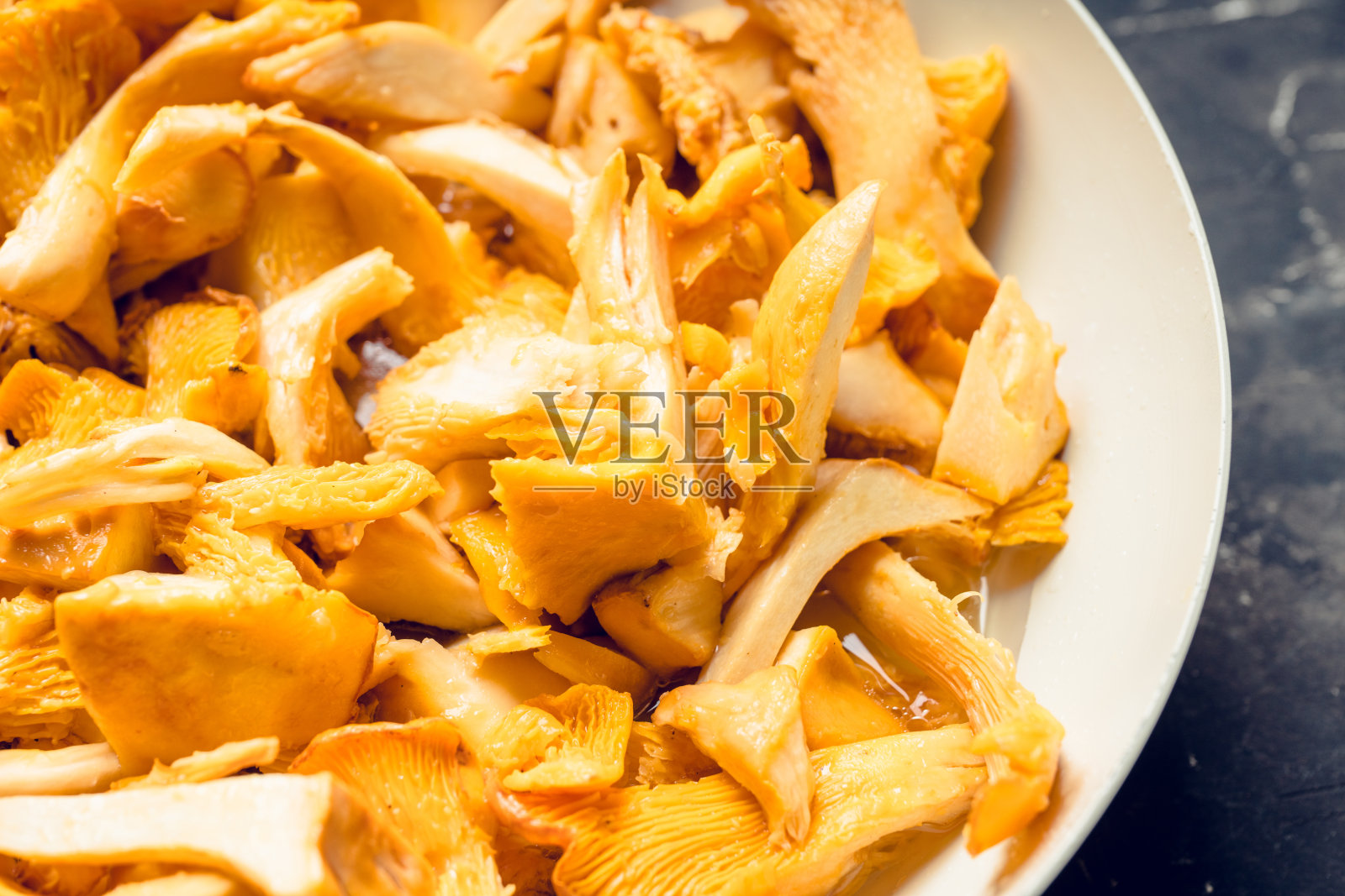 将鸡油菇切片放在平底锅上，准备煎炸照片摄影图片