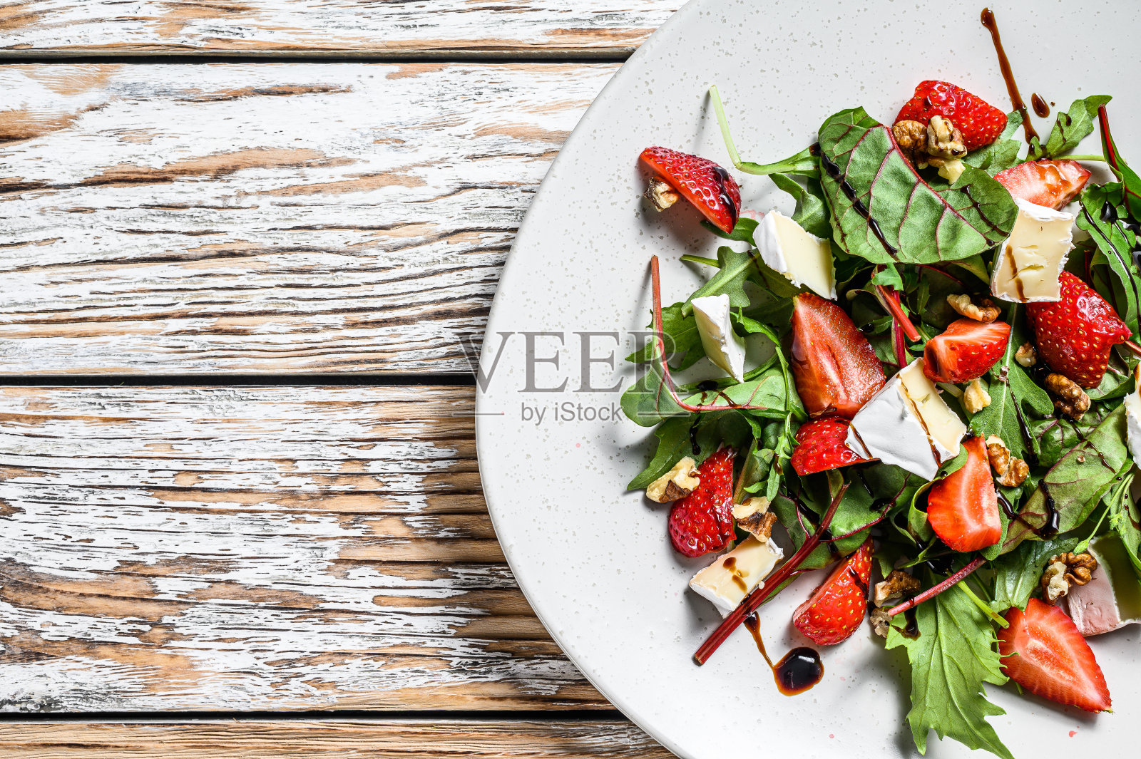 配乳酪、草莓、坚果、甜菜和芝麻菜的沙拉。白色背景。前视图。本空间照片摄影图片