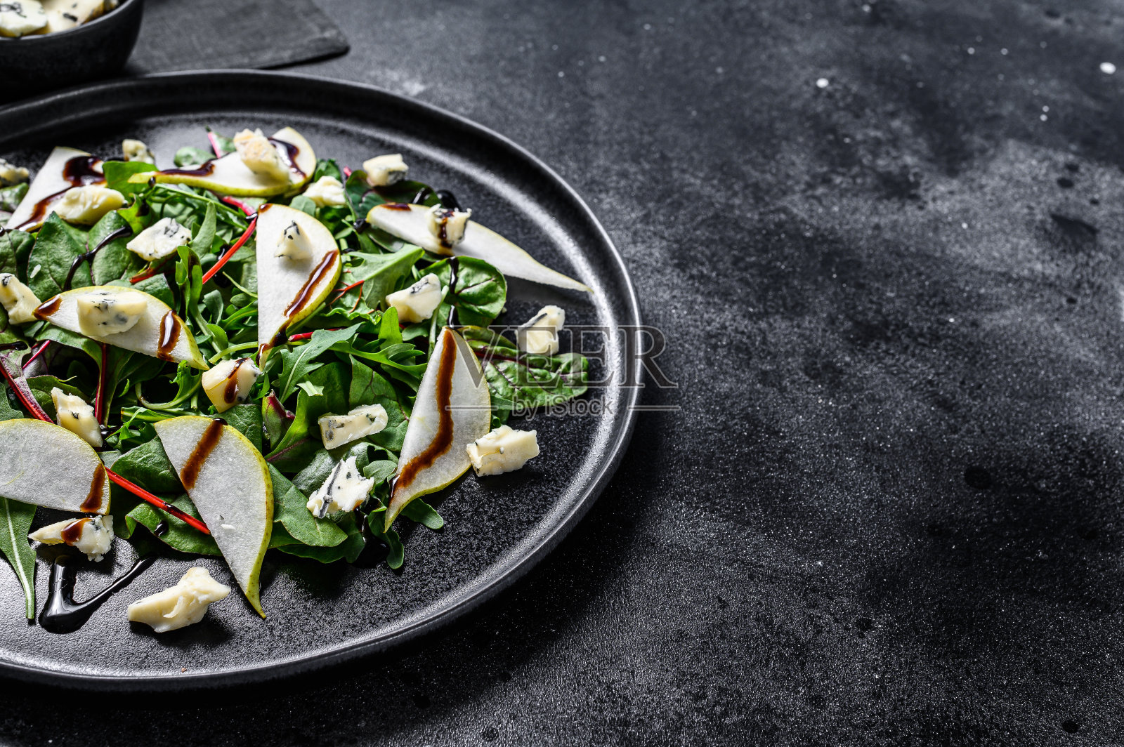 蓝奶酪沙拉，梨，坚果，甜菜和芝麻菜。黑色背景。前视图。本空间照片摄影图片