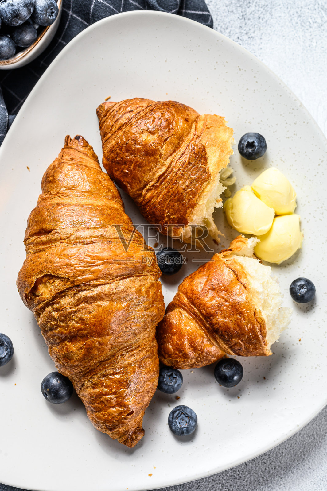 法式黄油牛角面包配蓝莓。灰色的背景。俯视图照片摄影图片